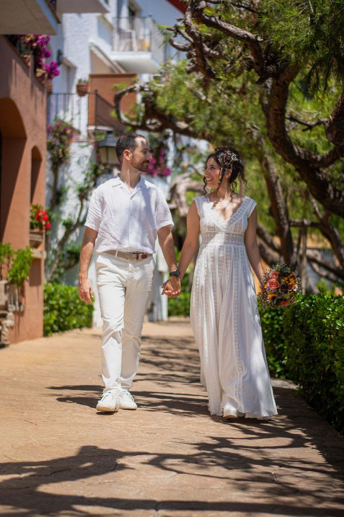 Pareja de novios paseando por un callejón con plantas y flores