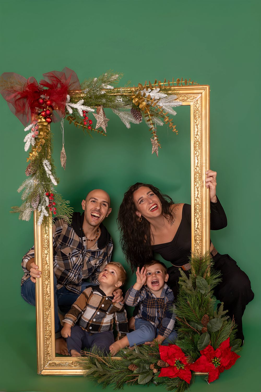 Familia riendo asomada a un marco dorado decorado con flores de Pascua sobre fondo verde