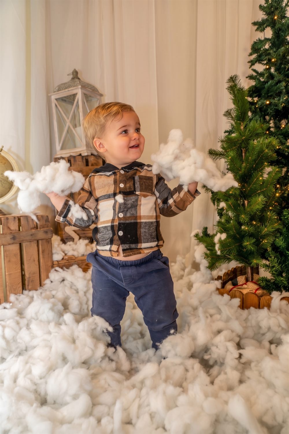 Niño jugando con la nieve del escenario navideño junto a los abetos